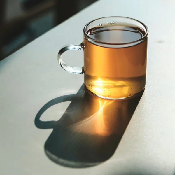 A glass mug of golden-amber tea in low sunlight