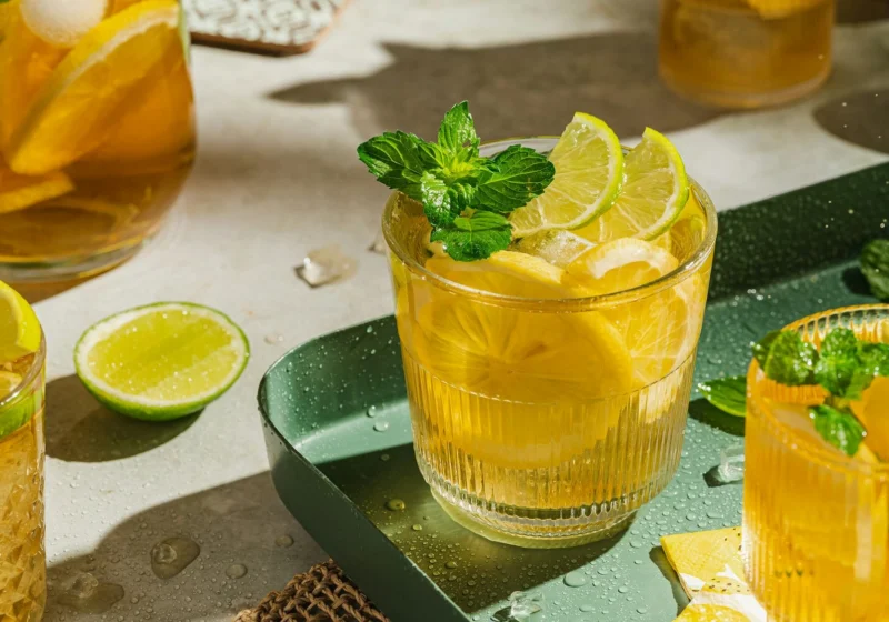 Glasses of iced tea with lemon and lime slices and mint in sunlight