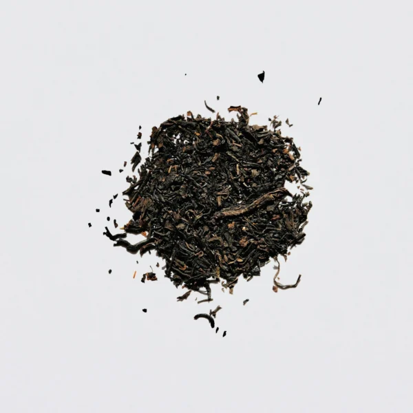A small pile of loose-leaf black tea on a pale background