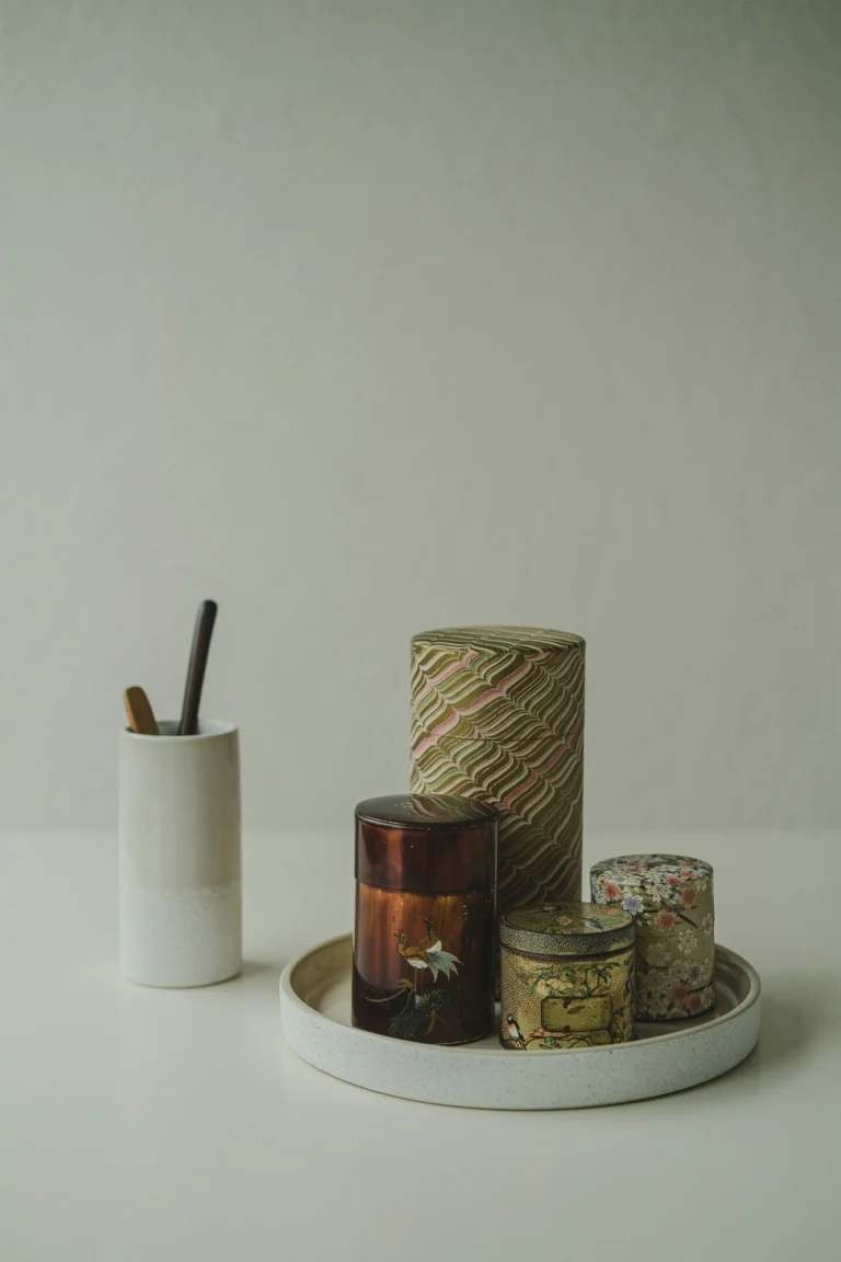 Tea caddies on a ceramic tray beside a cup of wooden scoops