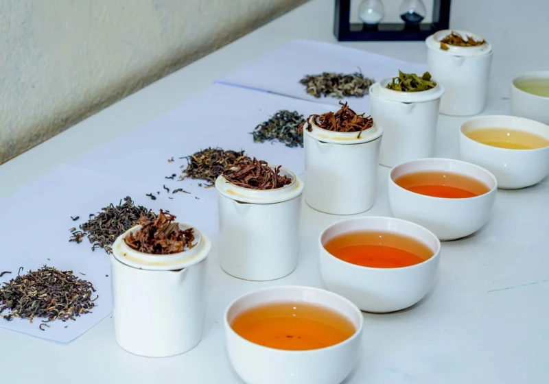 A tea tasting line-up of tasting mugs, bowls of tea and dry leaf samples