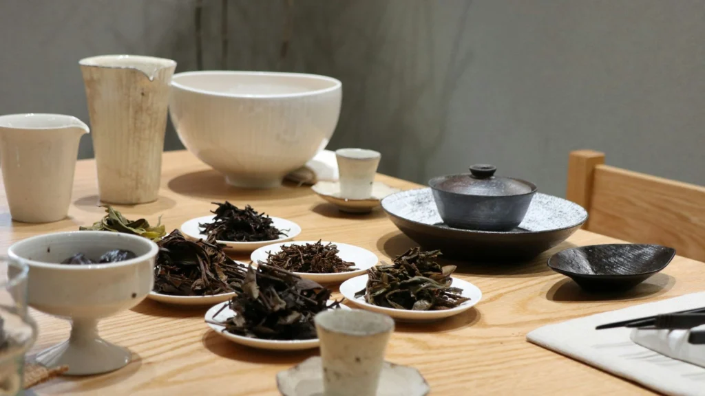 Several small plates of dark whole-leaf tea laid out for comparison